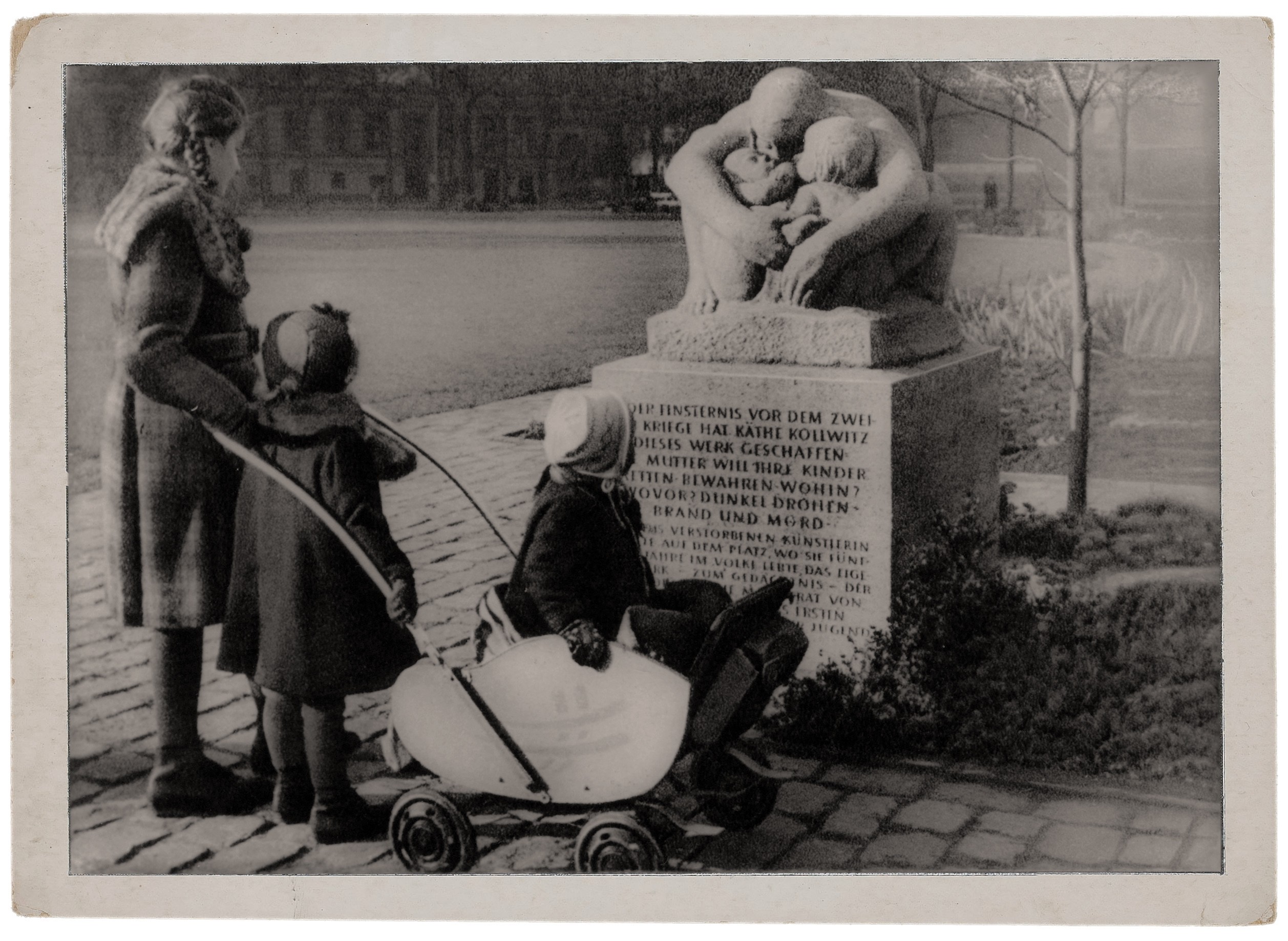 Käthe Kollwitz, Mutter mit zwei Kindern, Modell 1932–1936, 1949 ausgehauen von Fritz Diederich in Muschelkalk, aufgestellt 1950 auf Anregung von Gustav Seitz auf dem Berliner Kollwitzplatz gegenüber des ehem. Wohnhauses der Künstlerin, Fotograf unbek., historische Postkarte, Repro: Kollwitz Museum Köln
