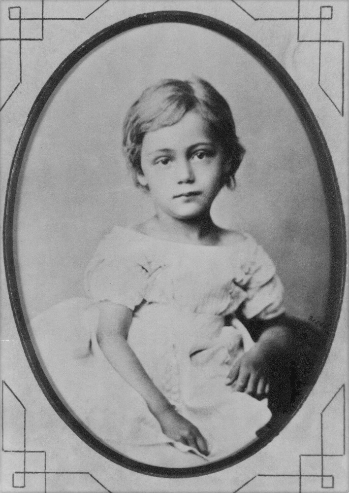 A photograph of Käthe Kollwitz, née Schmidt, aged around 5. She is wearing a white dress with short sleeves. Photographer unknown. A reproduction print of the photograph from the artist’s estate is held in the archives of Kollwitz Museum Köln, Inv. No. F-01.a-01.