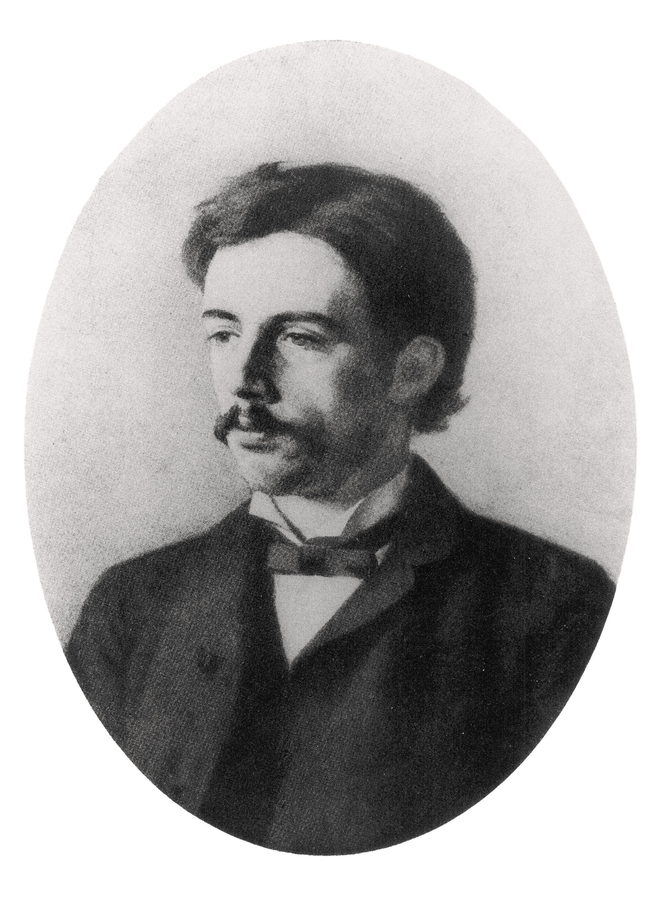 Dieses Schwarz-Weiß-Porträt, eine Fotografie eines nicht erhaltenes Gemälde von Käthe Kollwitz aus den Jahren um 1886/87, zeigt ein Dreiviertel-Brustbild ihres Bruder Konrad Schmidt als jungen Mann mit dunklem Haar und einem markanten Schnurrbart in einer ovalen Rahmung. Er blickt leicht nach links und trägt zeitgenössische, formelle Kleidung, bestehend aus einem dunklen Jackett, einer hellen Weste und einer dunklen Fliege. Der Hintergrund ist schlicht und hell gehalten.
