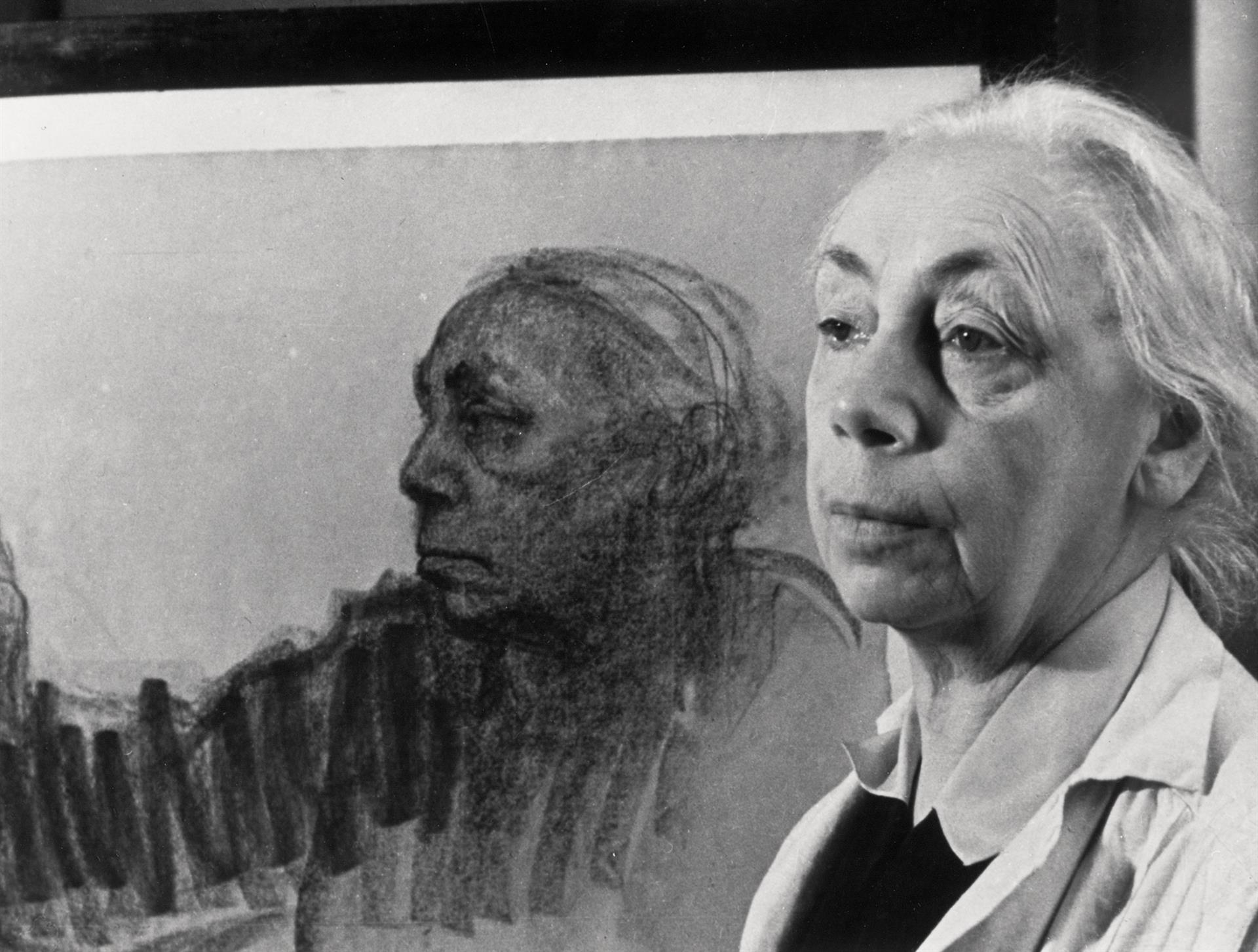 Käthe Kollwitz, 1935, in front of a self-portrait. Photographer unknown, Kollwitz estate © Käthe Kollwitz Museum Köln