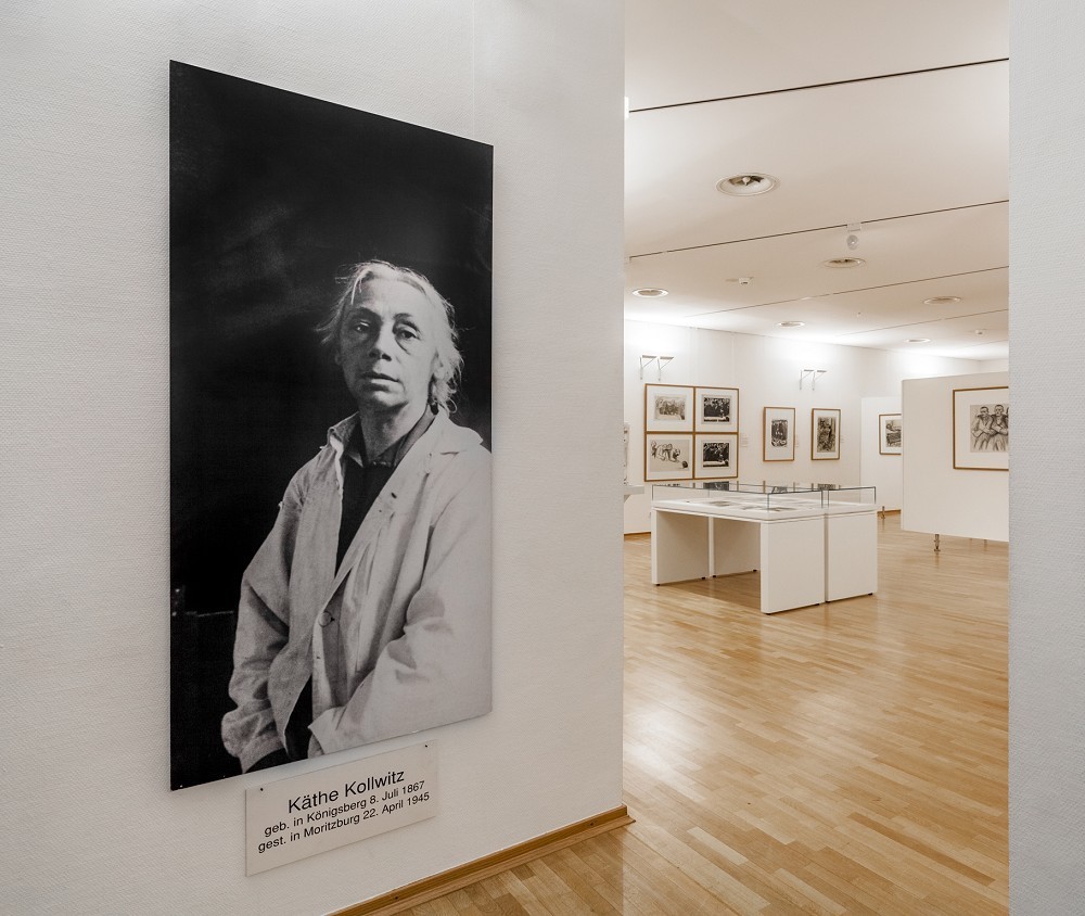 Das Farbfoto zeigt einen Blick in die Sammlungspräsentation des Jahres 2015: Im Vordergrund eine Fotografie von Käthe Kollwitz in ihrem Atelier. 